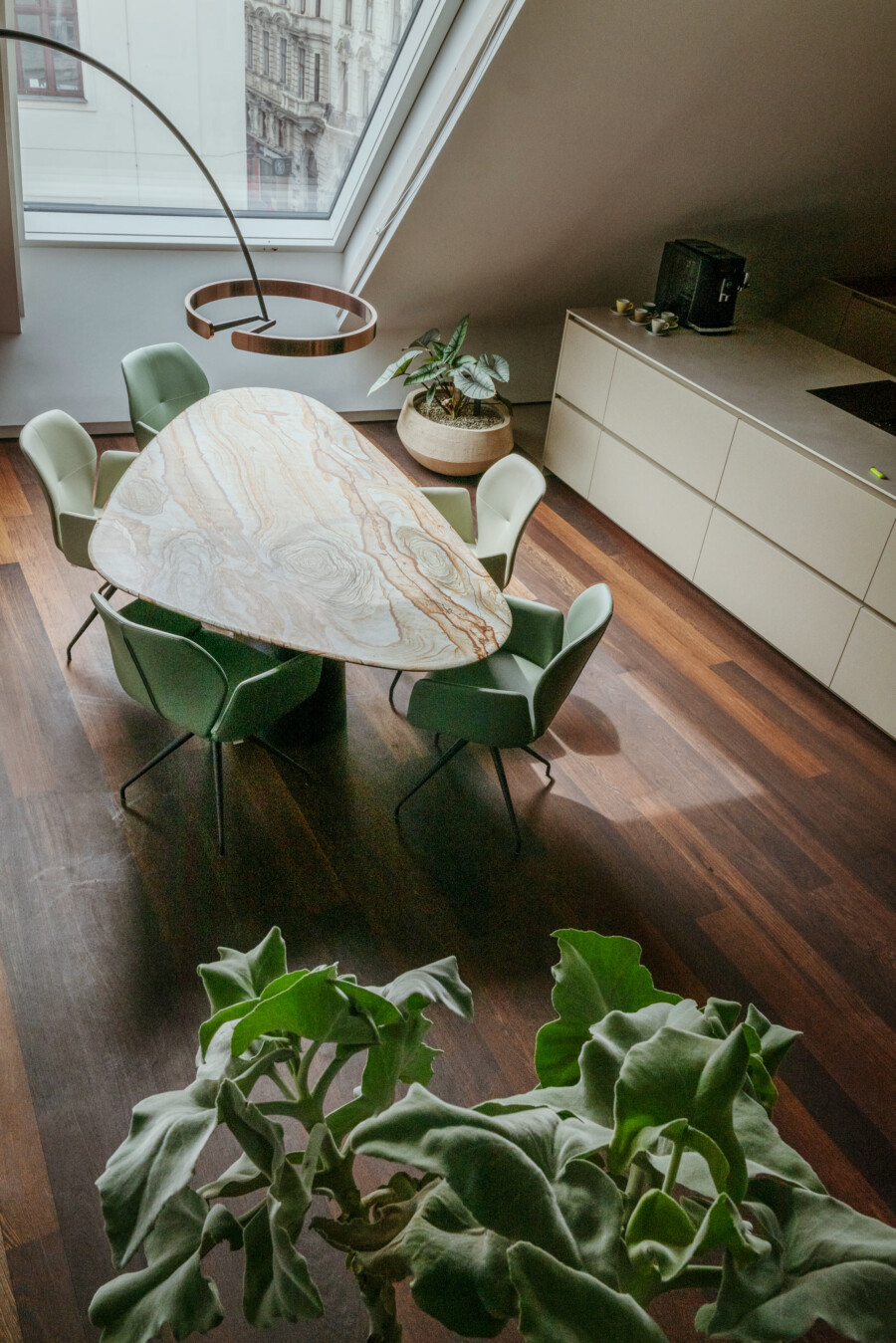 Dachgeschoss-Essbereich: ovaler Marmortisch, grüne Stühle; Ficus elastica am Fenster, Kalanchoe beharensis im Vordergrund.