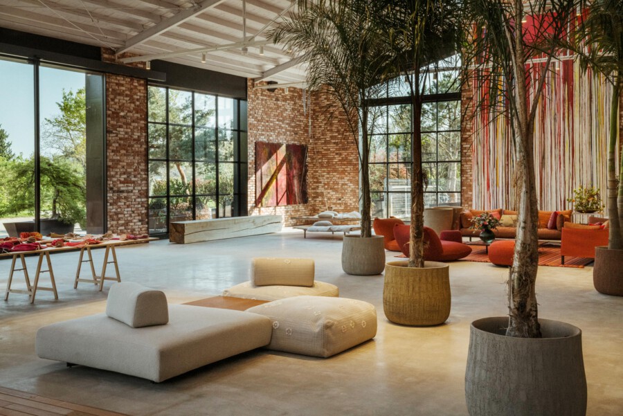 Moderne Innenraum-Lounge mit Dypsis lutescens-Palmen, bequemen Sitzgruppen, Backsteinwänden und großen Glasfronten.