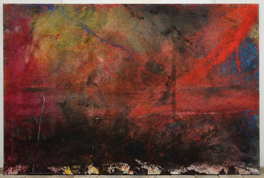 Abstrakte Leinwandmalerei mit roten, braunen und schwarzen Farbschichten; blaue Akzente, auf dem Boden vor heller Wand gelehnt.