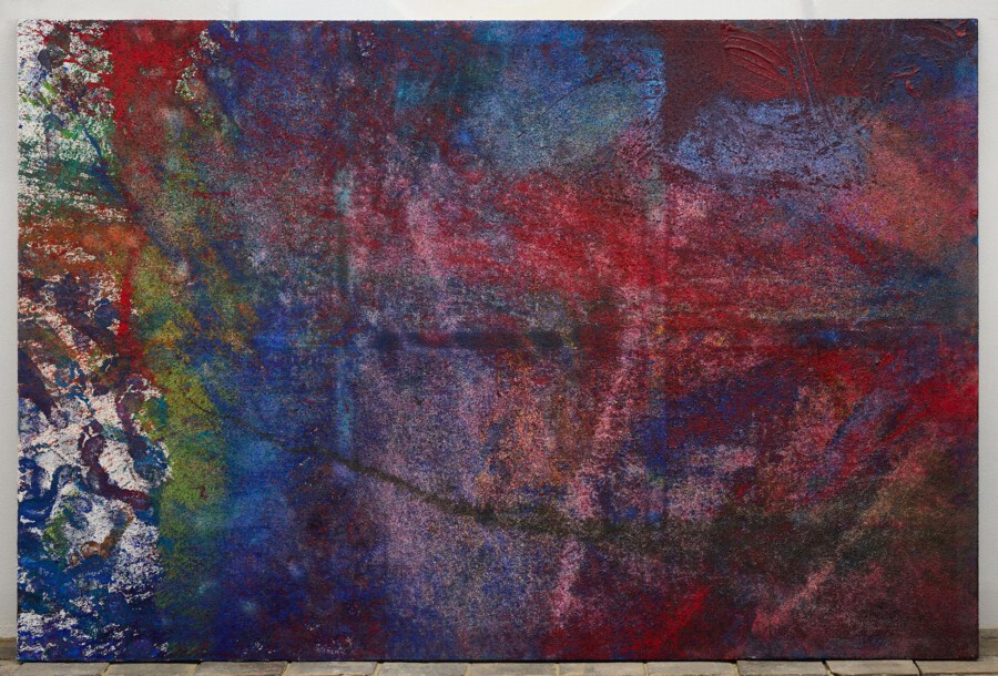 Abstraktes Gemälde mit dichten Rot-, Blau- und Grüntönen, grobe Textur, links helle Formen, vor weißer Wand auf Holzdielenboden.