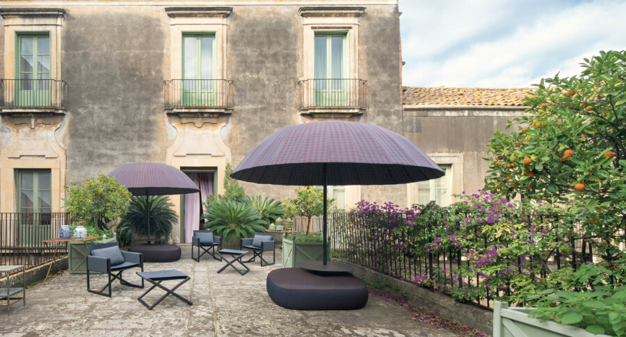 Courtyard garden with Citrus × sinensis orange tree, Bougainvillea glabra vines, Cycas revoluta cycad, striped umbrellas, and seating.